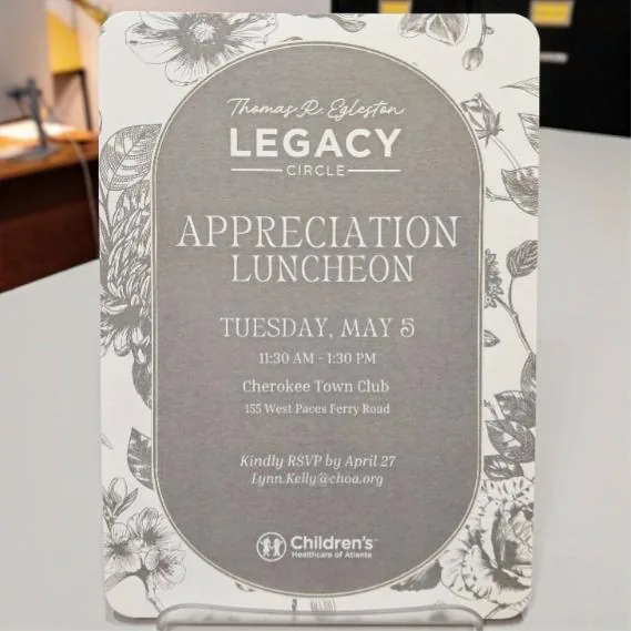 Legacy Circle Appreciation Luncheon invitation with a grey toile floral border, arched panel and rounded corners, standing in an acrylic holder