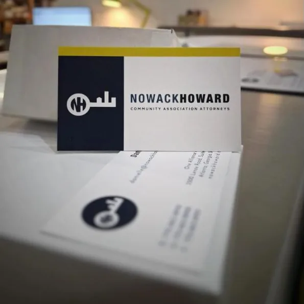 Business cards with a navy block and chartreuse top band, one standing and one face-down showing the reverse